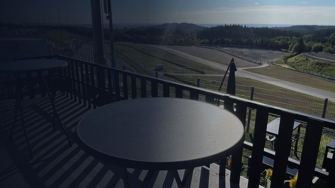Dachterrasse mit Tisch und Blick über eine Rennstrecke.